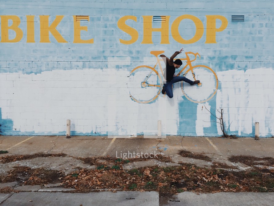BIKE SHOP sign and man leaping 