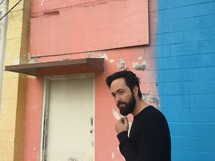 man with a beard in front of a multi colored wall 