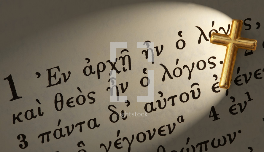 Gold cross on Greek Bible text.