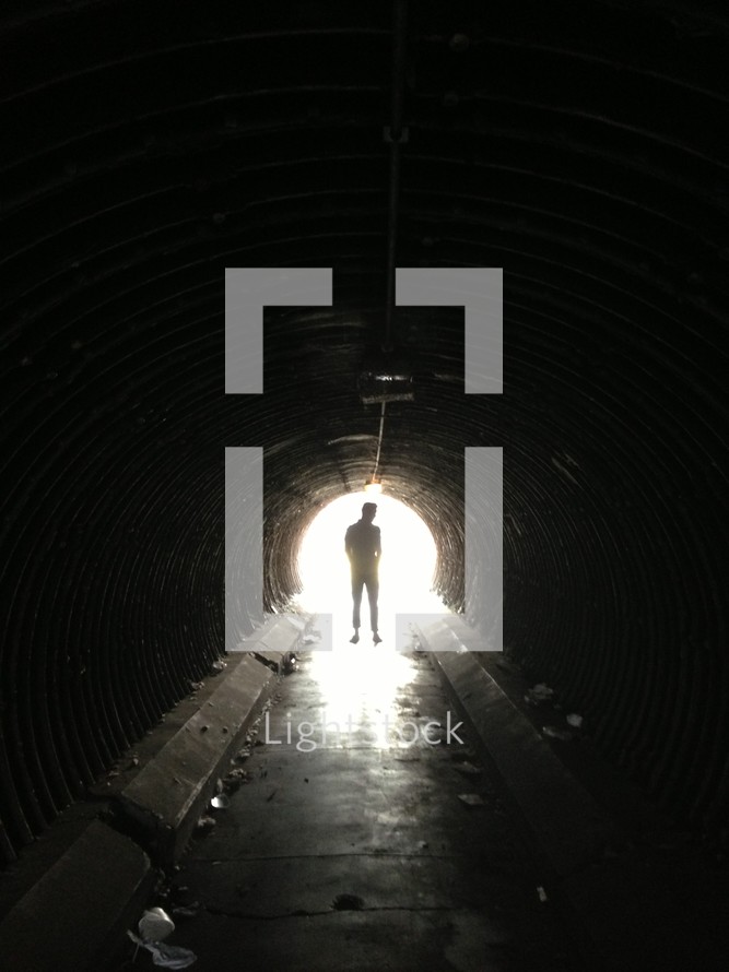 man walking towards the light in a tunnel 