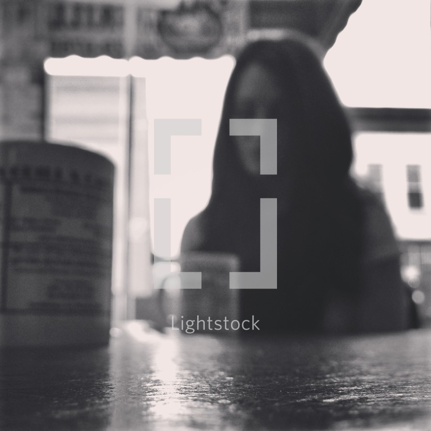 blurry image of a woman sitting in a coffee shop