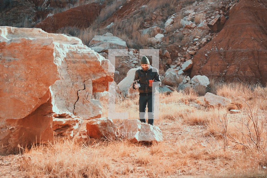 man standing beside of red rocks 