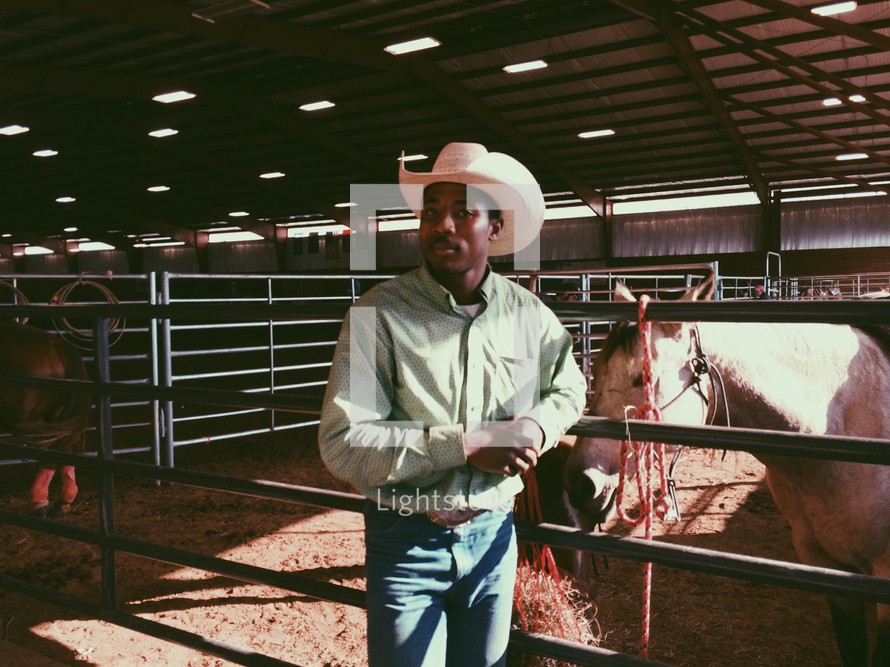 cattle rancher standing near a horse in a stable 