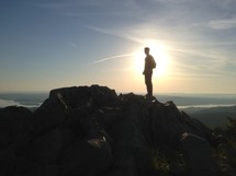 silhouette of a man on a mountain top at sunrise