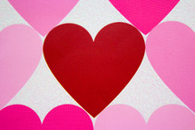 A red heart between hearts in shades of pink.