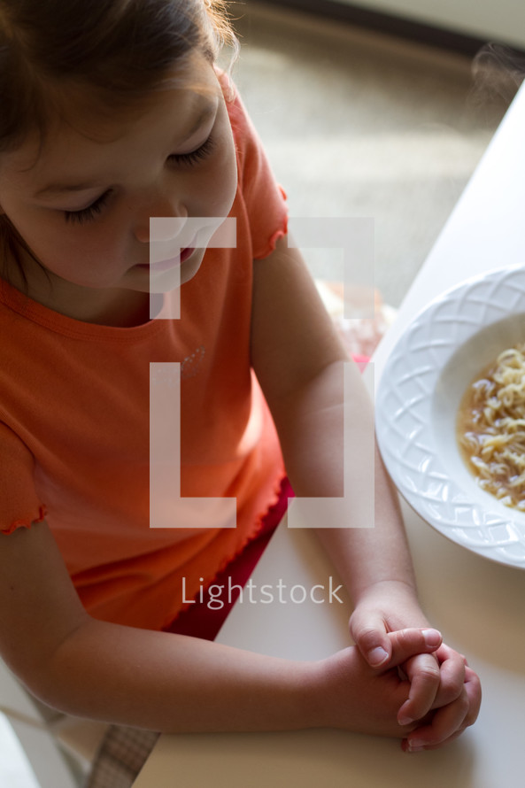 a girl child praying at mealtime 