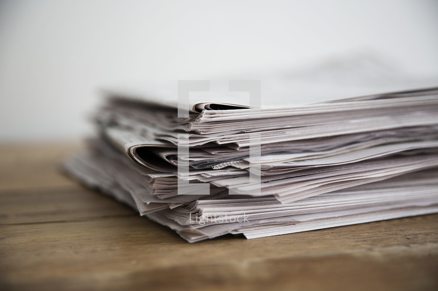 stack of newspapers on a wood table.
