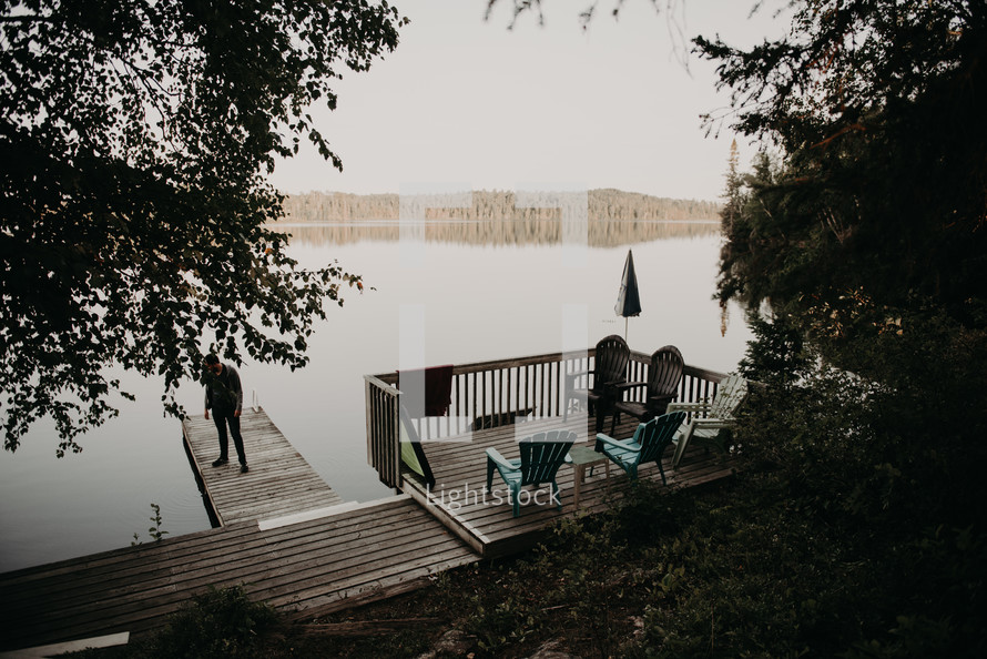 man standing on a dock at a lake 