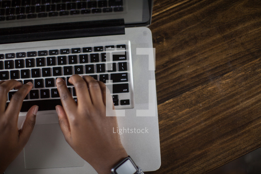 hands typing on a laptop keyboard 