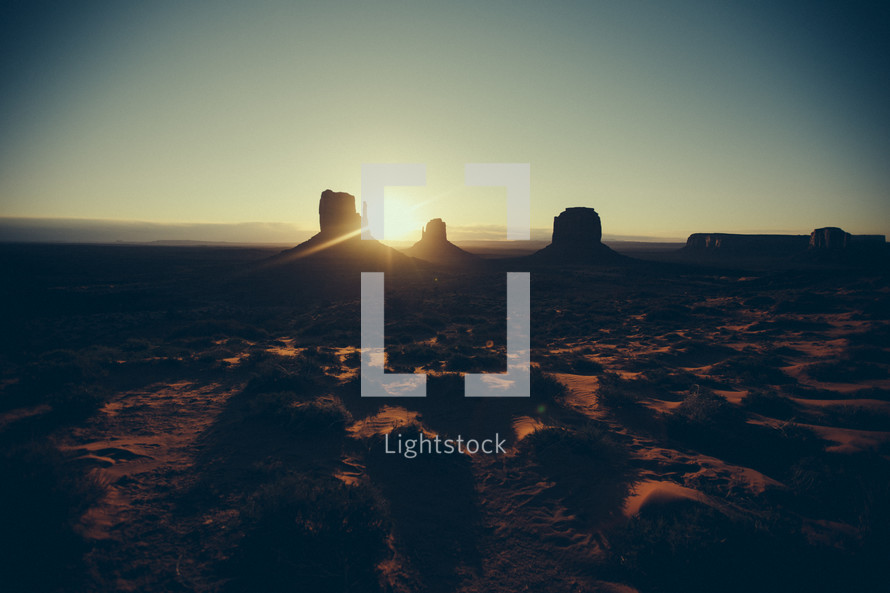 Sunset on a desert landscape with silhouettes of buttes.