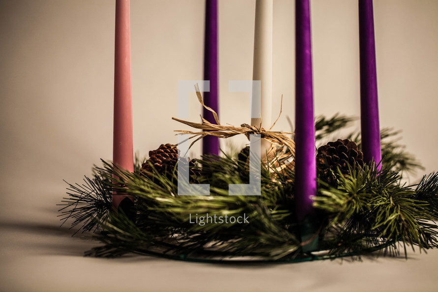 Five candles in pine wreath with pine cones.