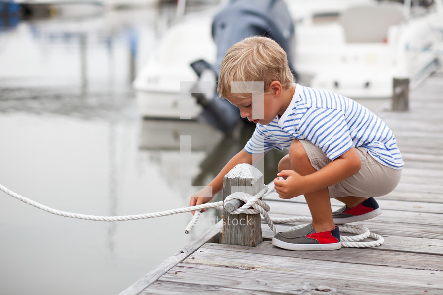 boy child untying a rope at a marina 