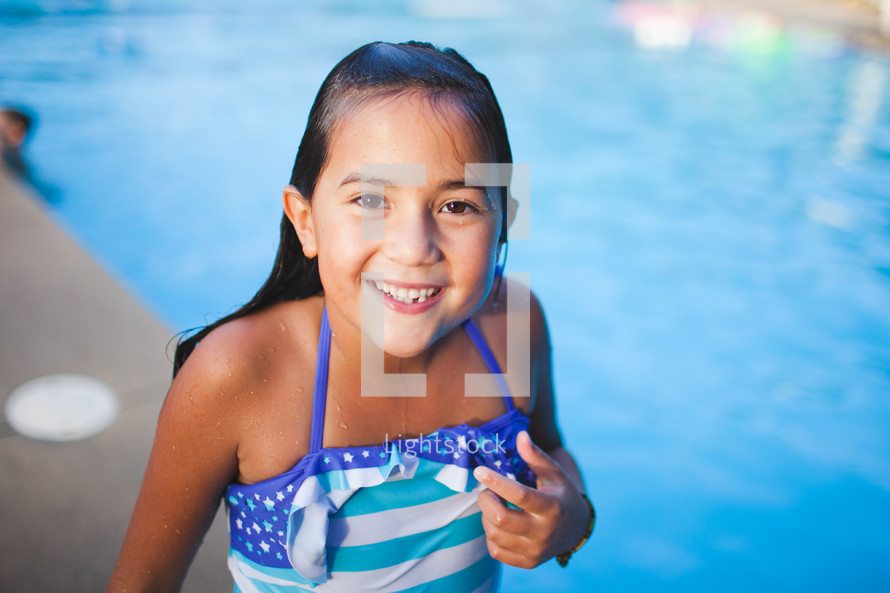 a girl child in a bathing suit by a swimming pool 