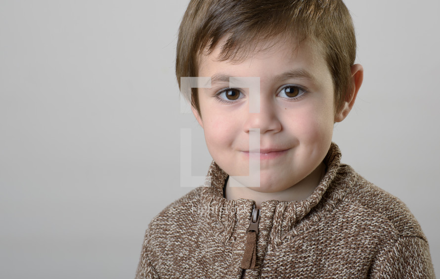 smiling toddler boy in a sweater 