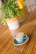 cappuccino in a mug on a table and house plant 