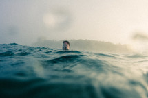 man standing in ocean water up to his head, 