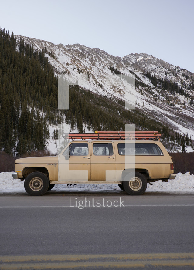 vintage suburban parked in front of a snow covered mountain 