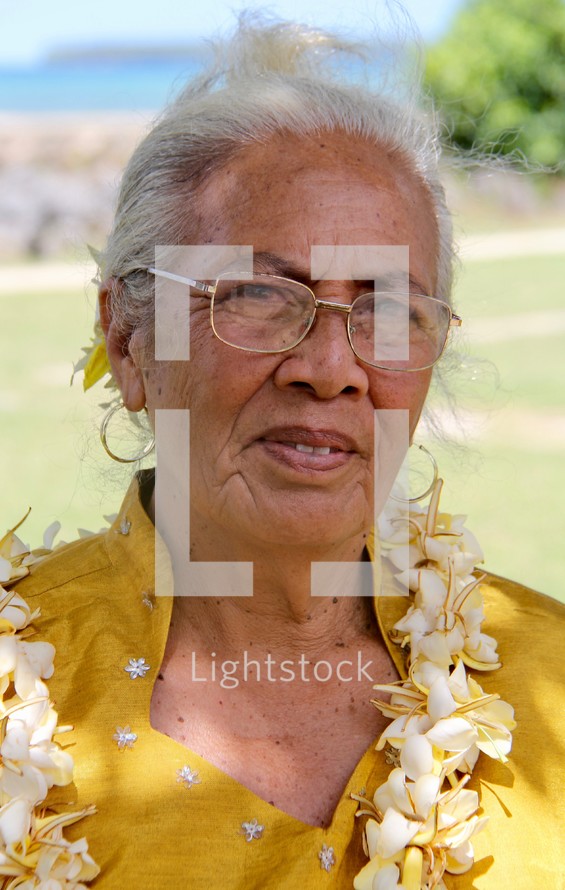 an elderly woman wearing a lei 