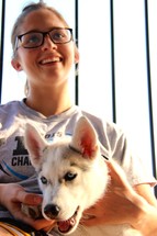 a teen girl holding a husky puppy