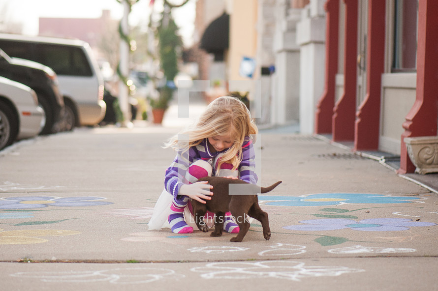 girl child playing with a puppy 
