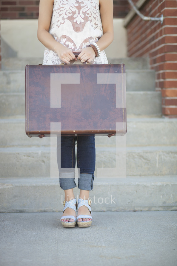 woman standing holding a suitcase 