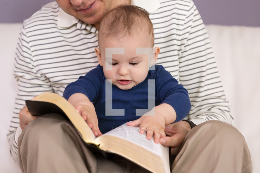 father and infant son reading a Bible together 