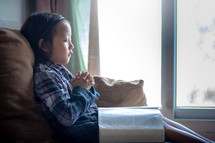 a girl praying with a Bible in her lap 