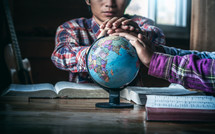 hands on a globe during a small group Bible study 