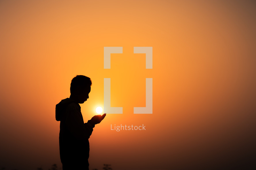 Boy praying to God on the mountain with light sunset background, Christians should worship and thank God, Christian silhouette