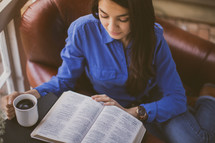 A woman reading a Bible drinking coffee 