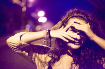 a young woman peeking through her hands 