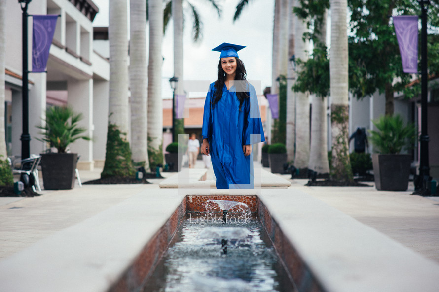 teen girl standing in her cap and gown at graduation 