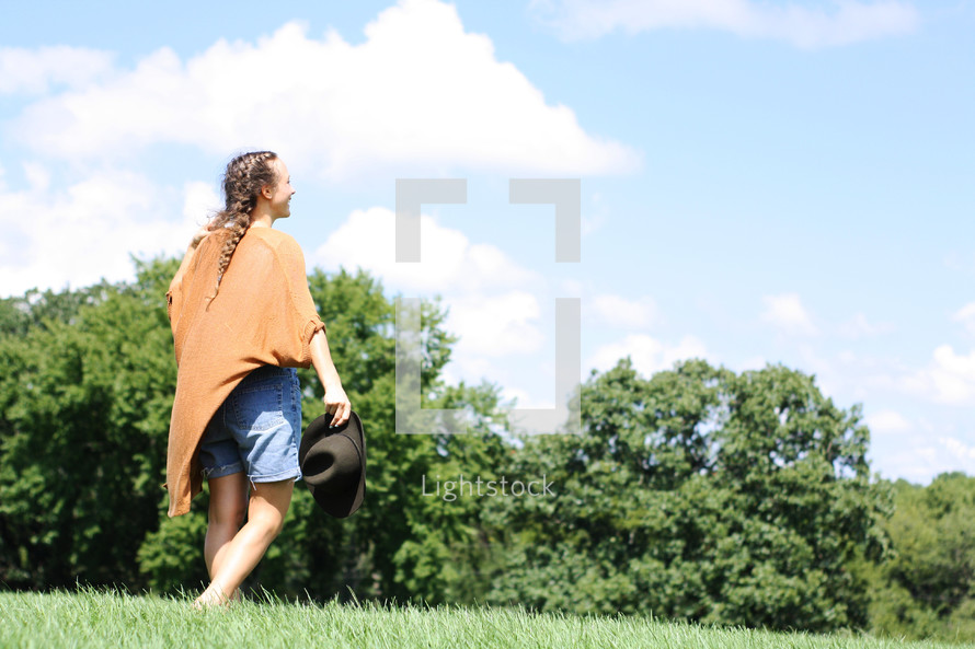 a woman walking through a field of grass