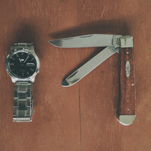 a pocket knife and watch on a table 