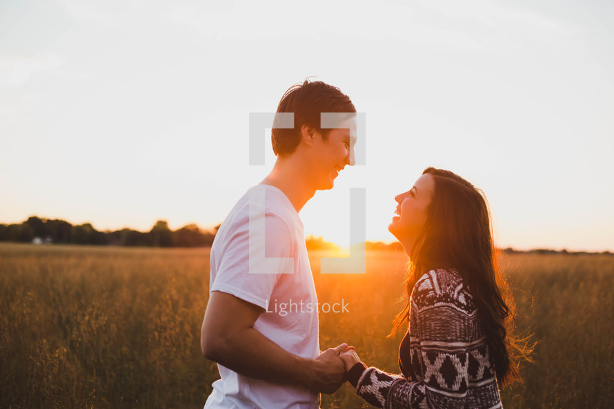 a couple holding hands in a field at sunset 