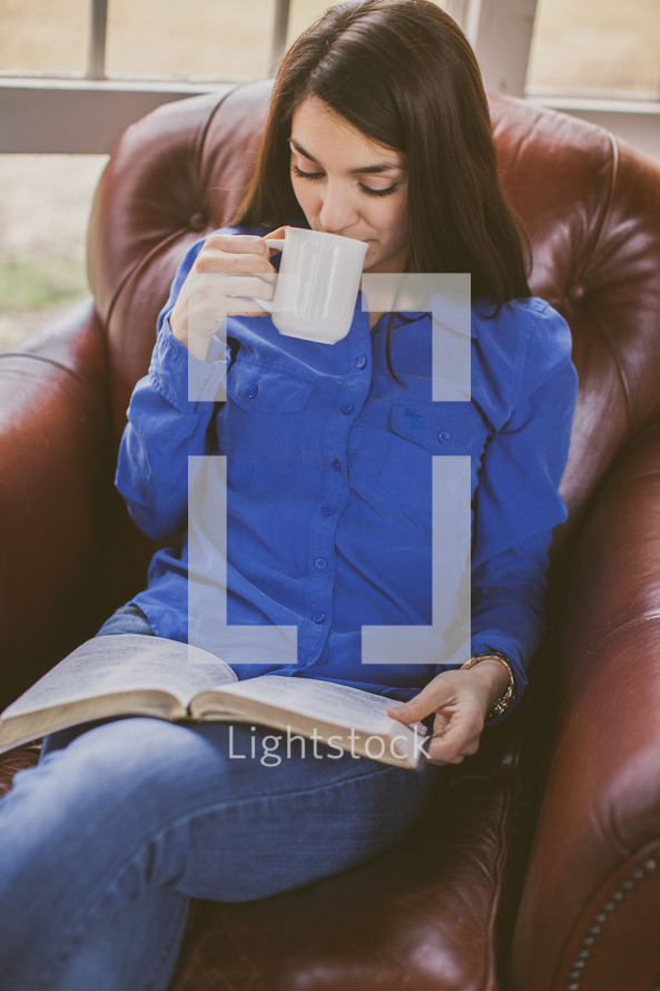A woman drinking coffee and reading a Bible 