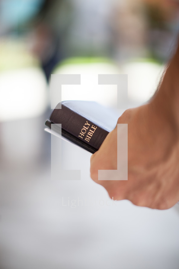 hand holding a Bible and bulletin 