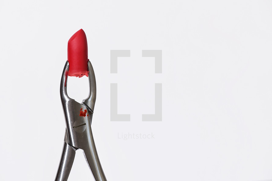 Conceptual Dental pliers tool and red lipstick