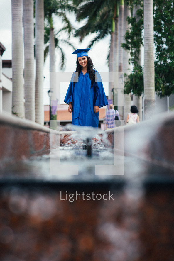 a graduate standing under palm trees 