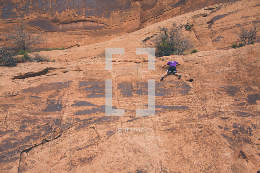 a man rock climbing a steep cliff 