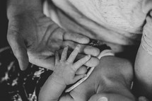 an infant's hand holding onto father's hand 