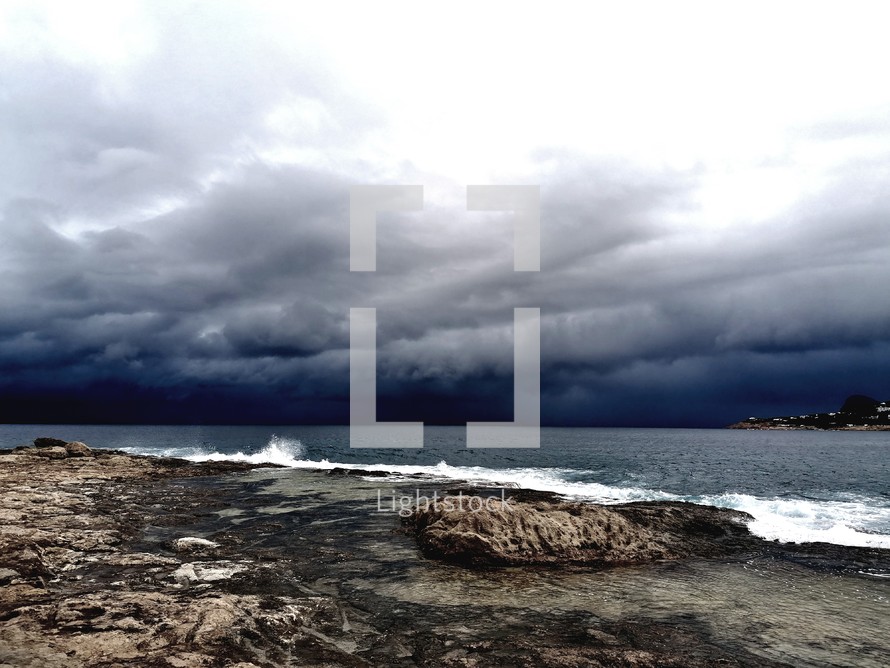 dramatic rocky shore with a storm approaching on the horizon