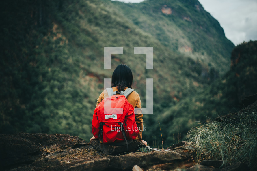 a woman resting while backpacking through a forest 