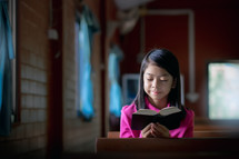 a girl reading a Bible in an empty church 