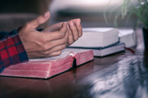 a man with praying hands over an open Bible 