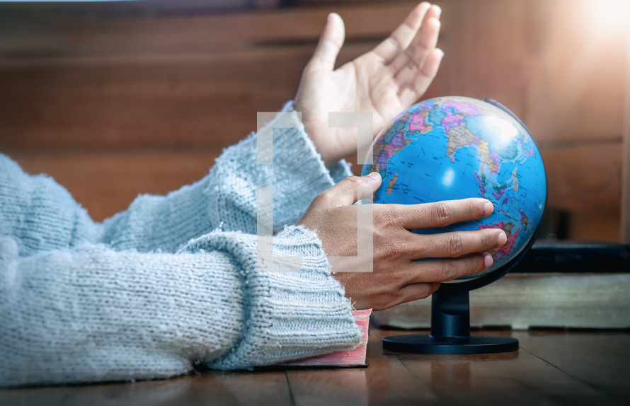 praying hands beside of a globe 