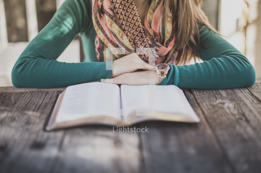 A woman sitting at a table reading the Bible