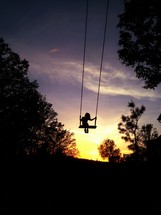 silhouette of a child on a swing 