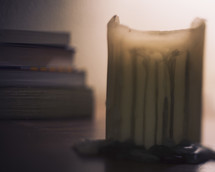 melting candle and a stack of books 