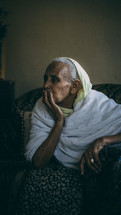An elderly woman sitting and concentrating on something ahead